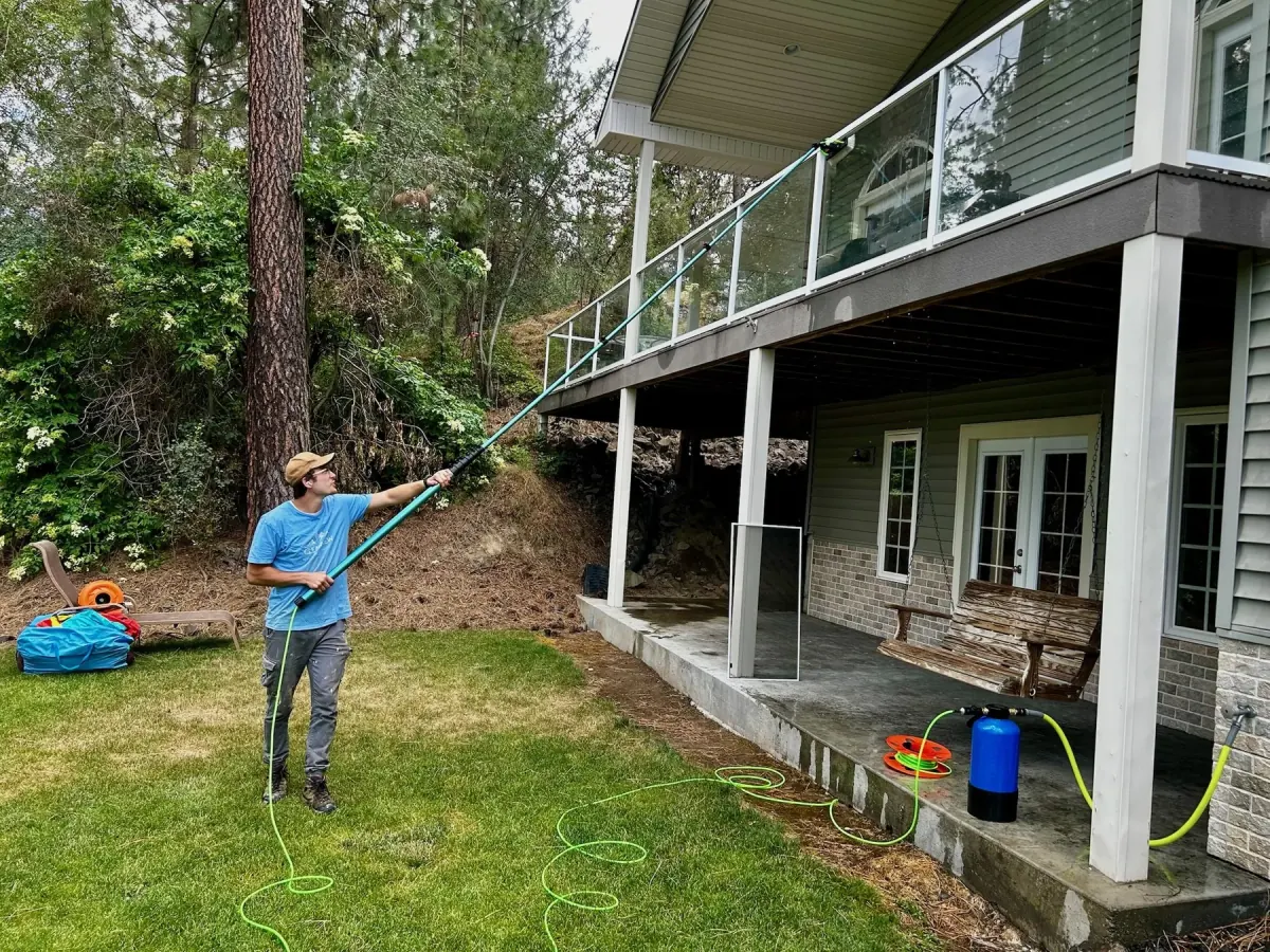 Nate Meeks cleaning second-story residential windows in the Spokane area with a water-fed pole system